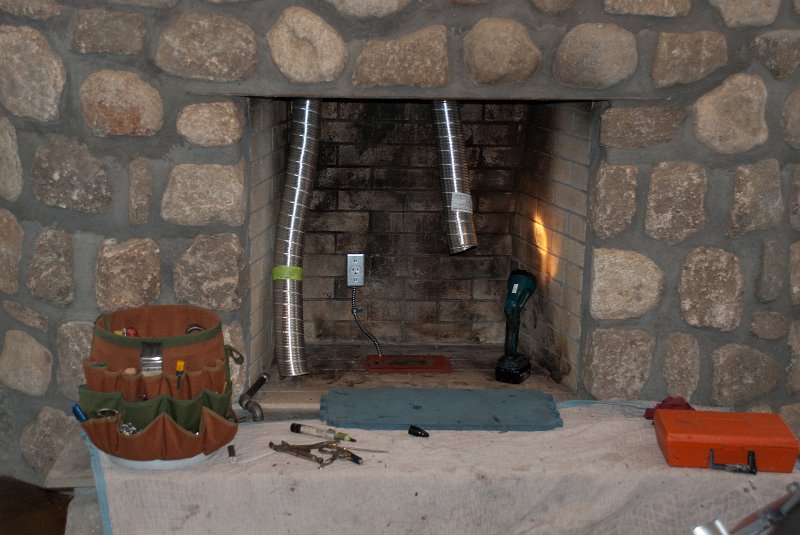 DSC_9091.jpg - The ducts appear below.  In the fireplace, left to right: Gas stub (black pipe), air intake duct, electrical outlet, and exhaust duct.