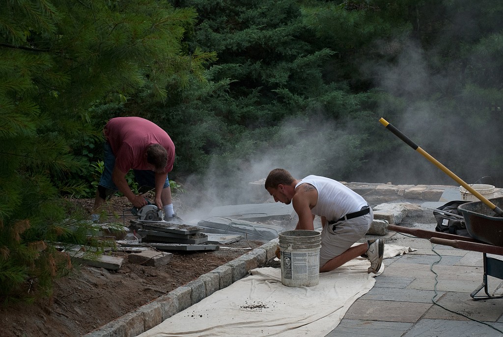 DSC_8698.jpg - Harold raises some dust by cutting flagstones while Austin is putting mortar between the curb stones.