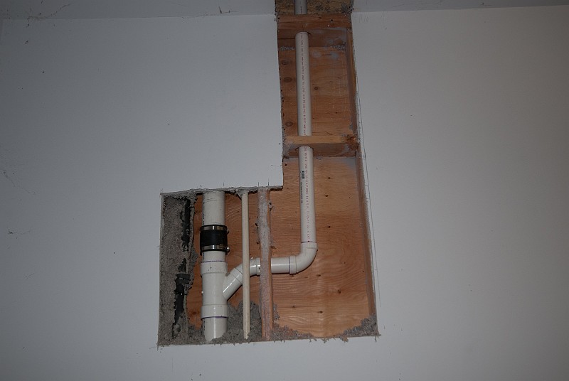 DSC_2850.jpg - Darren connected the shower drain line to the other fixtures' main drain pipe.  More cut sheetrock and even more cascading insulation resulted.